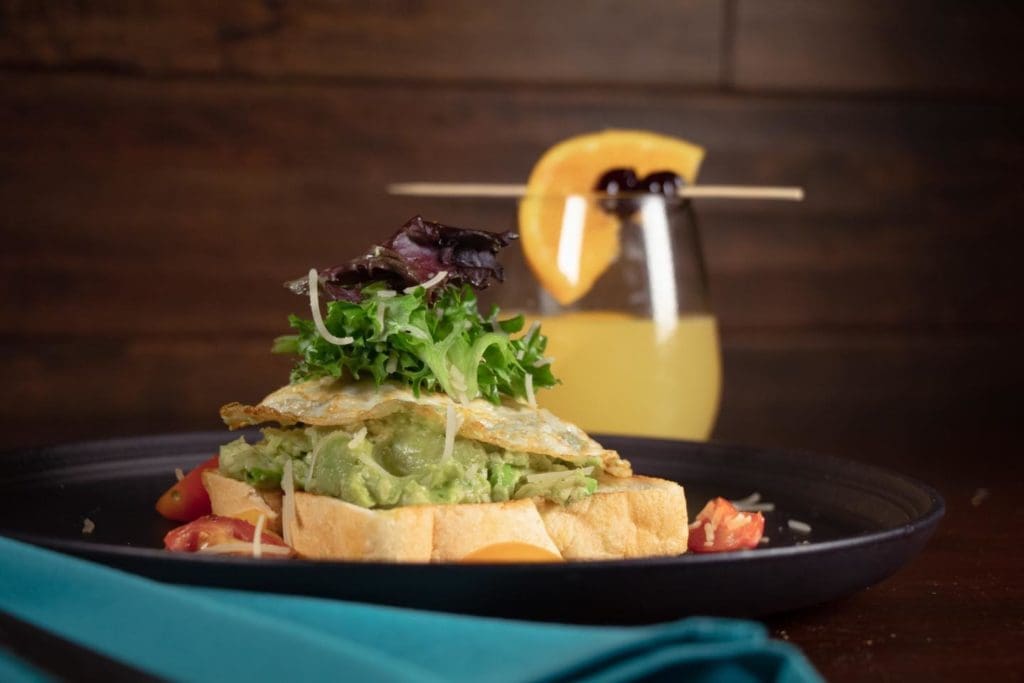 Fried egg topped avocado toast pairs well with a mimosa at brunch.