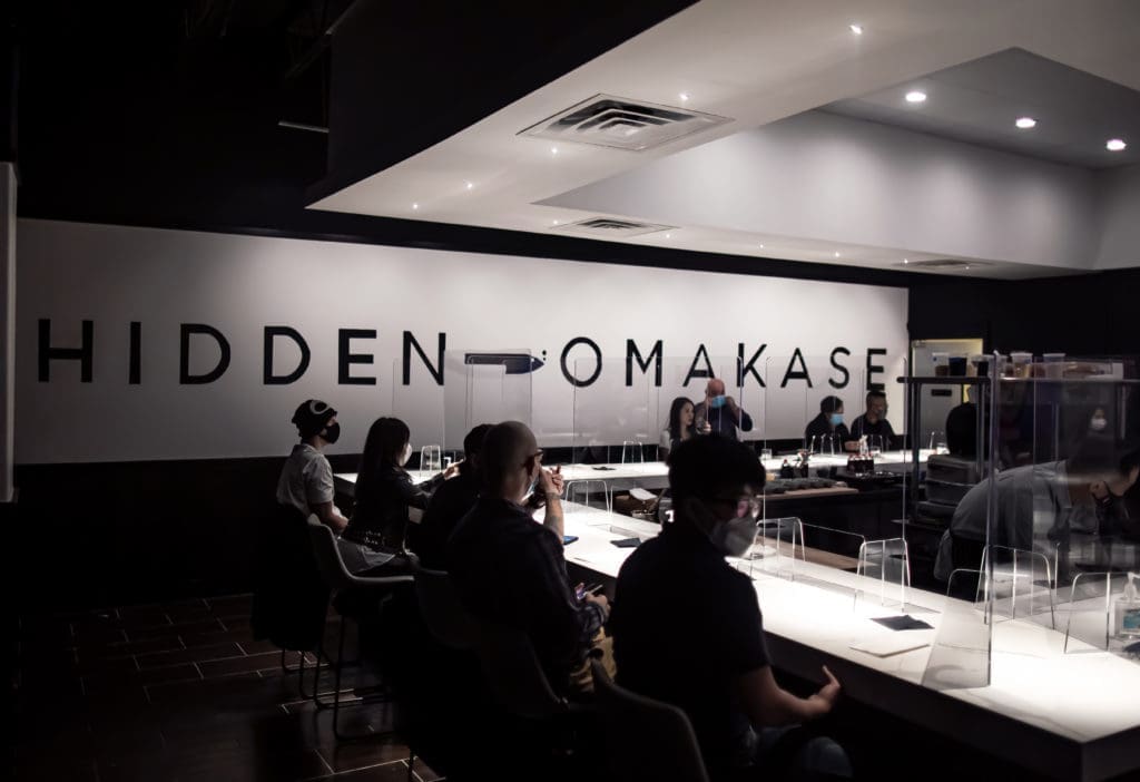 Diners sit socially distanced at Hidden Omakase's U-shaped counter top with Plexiglas dividers. (Photo by Katoe Productions)
