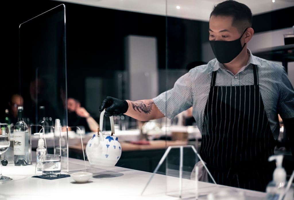 Hidden Omakase chef Billy Kin pours tea for a diner in a socially-distanced dining area. (Photo by Katoe Productions)