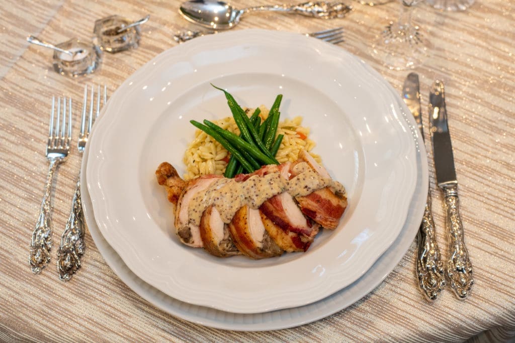 Bacon wrapped chicken breast stuffed with gruyère, mushroom and herbs, topped with Pommery mustard sauce, served with orzo pilaf and haricots verts and yeast rolls. (Photo by CatchLightGroup)