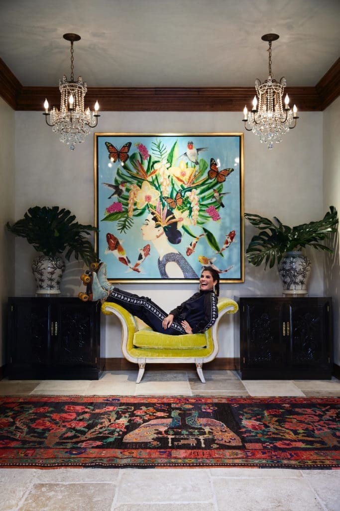 In the foyer, April Manson in her Moxie roller skates beneath a painting by New Orleans artist Ashley Longshore. Bench by Cuellar Custom Upholstery, in Pierre Frey velvet. Antique Turkish dowry rug. Vintage Henredon chests. Chandeliers original to the house. (Photo by Pär Bengtsson)