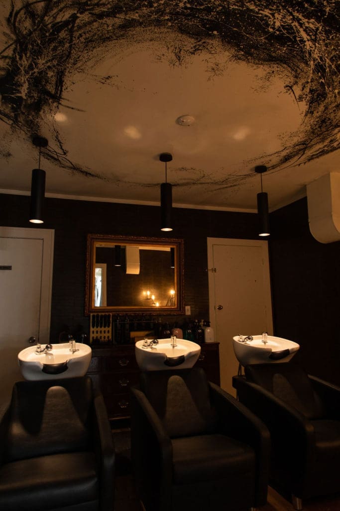 The wash room at Volume Social Club is purposely dark for client privacy. Artwork on the ceiling is a special Sergio Morales touch. (Photo by Leah Wilson)