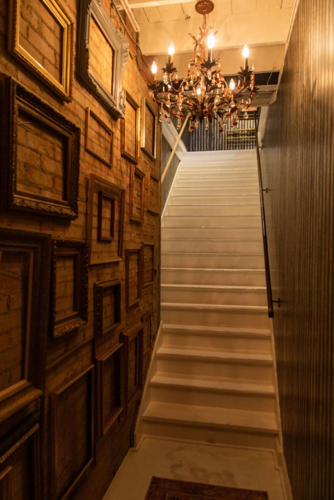 The art-lined stairway that leads to the second floor Volume Social Club salon. (Photo by Leah Wilson)