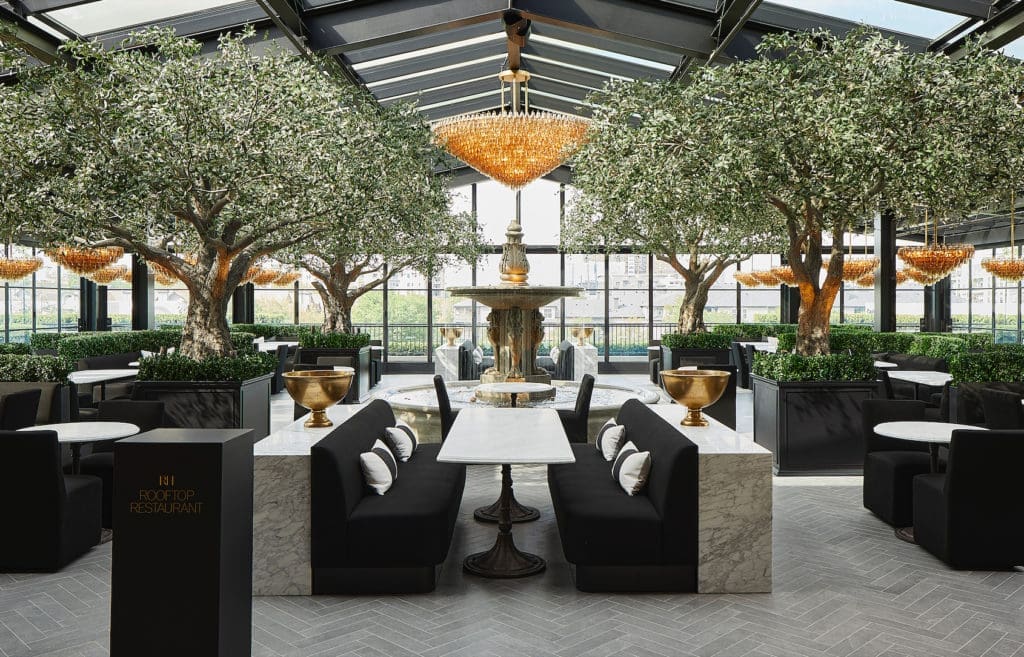 Inspired by classical European gardens, the Rooftop Restaurant and Park seamlessly brings the outdoors in with towering heritage olive trees, statement chandeliers, and an atrium with retractable glass walls (Photo by R2ro Photography)