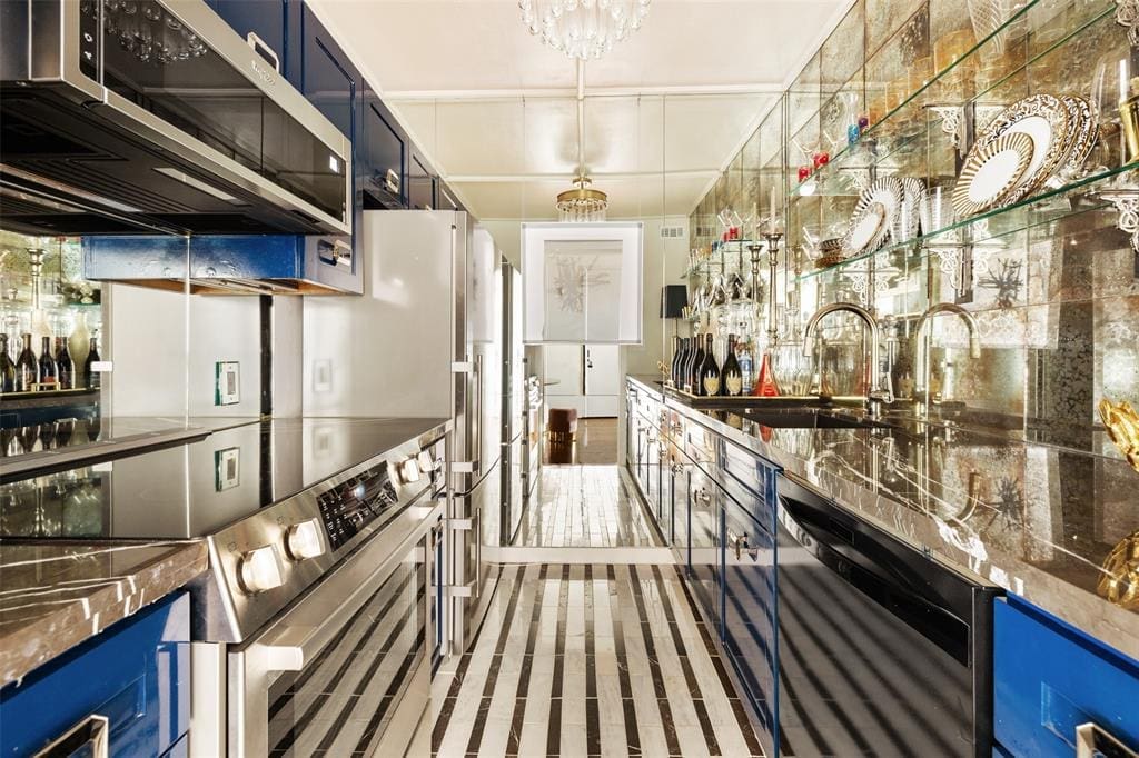 Antique-mirrored backsplashes, cabinetry in navy high-gloss lacquer, and countertops in Pietra gray marble add up to a unique kitchen in this condo at 1400 Hermann. 