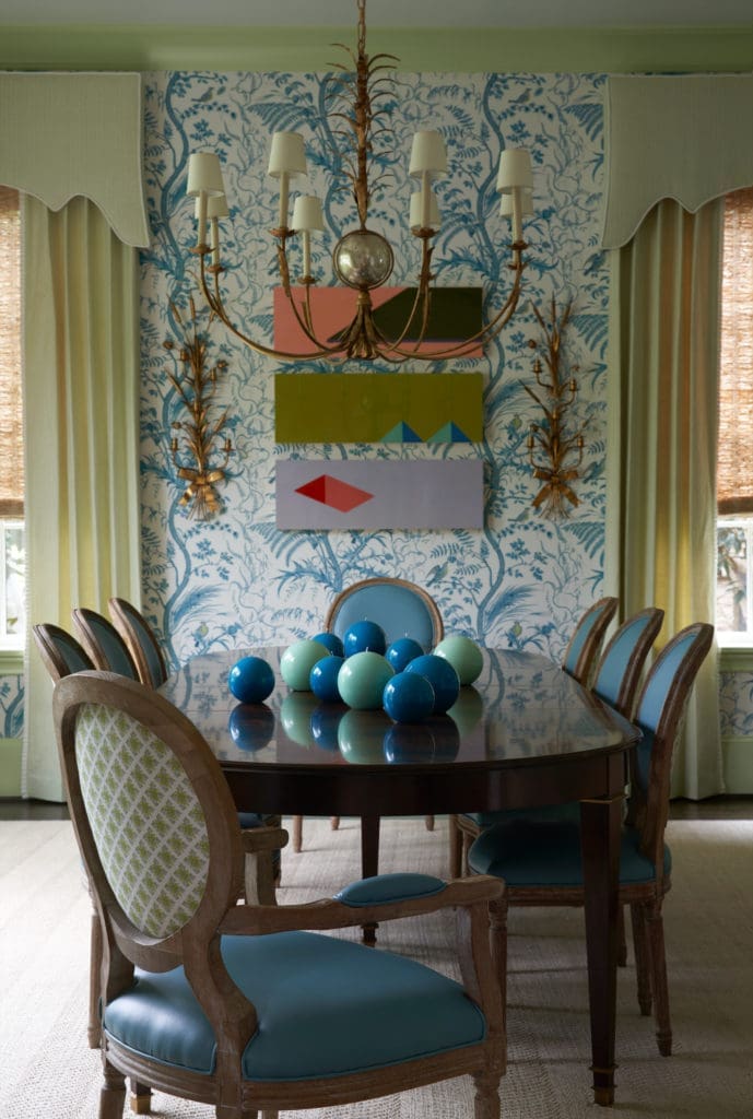 In the dining room, Brunschwig & Fils wallpaper. Cornice and draperies in Blithfield fabric, London. Chair backs covered in Raoul Textiles fabric. Visual Comfort chandelier. Artwork from Galleri Urbane. (Photo by Pär Bengtsson)