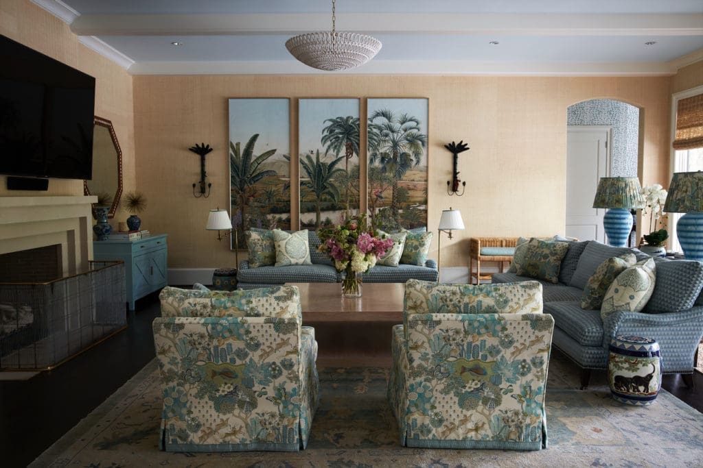 In the family room are framed panels of Iksel Decorative Arts hand-painted wallpaper from Schumacher. Bunny Williams lamps with Fermoie fabric shades. Chairs, pillows in Mulberry Home fabric. Romo chenille on sofas. Antique Oushak from Farzin Rugs. Madre chest, coffee table. Antique sconces. (Photo by Pär Bengtsson)