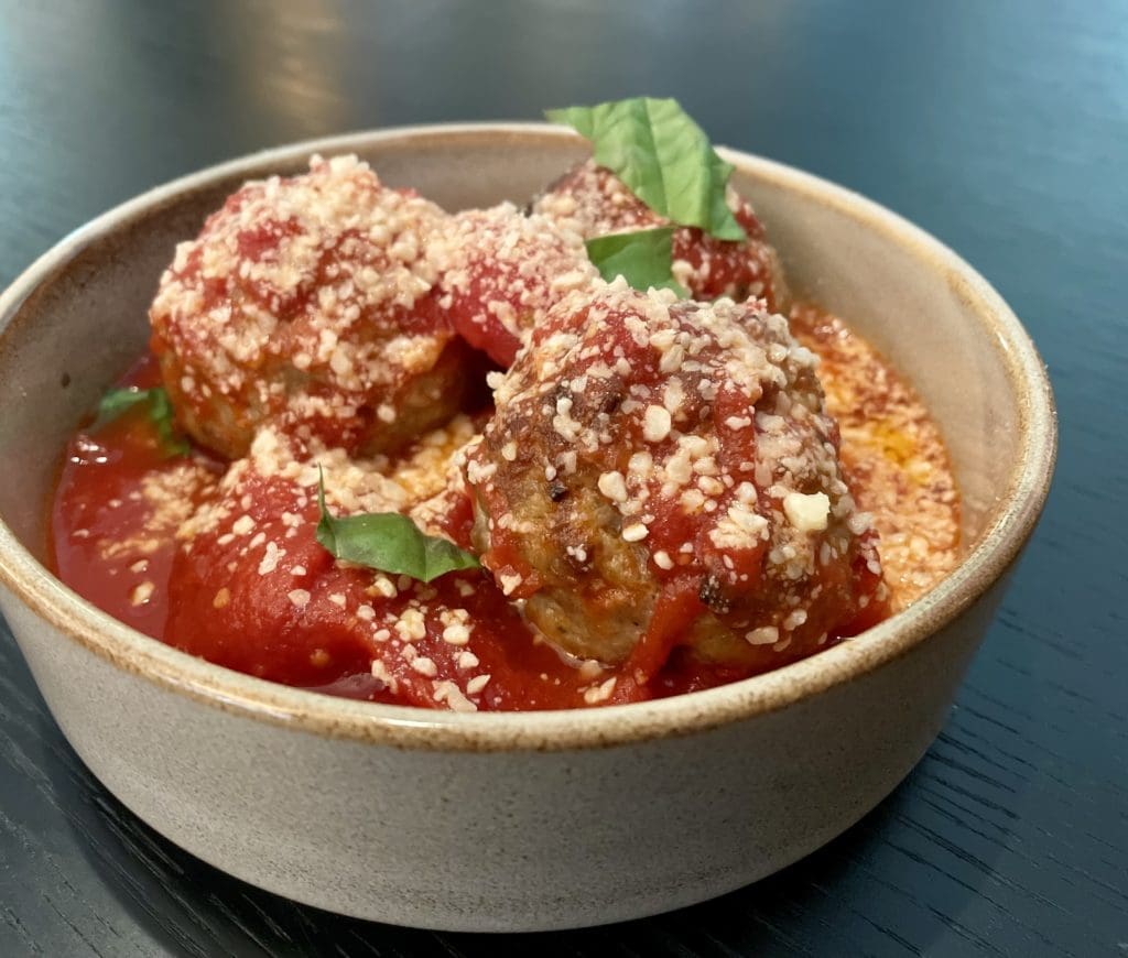 Delicate meatballs in house marinara with fresh shreds of basil. Photo by Courtney Dabney. 