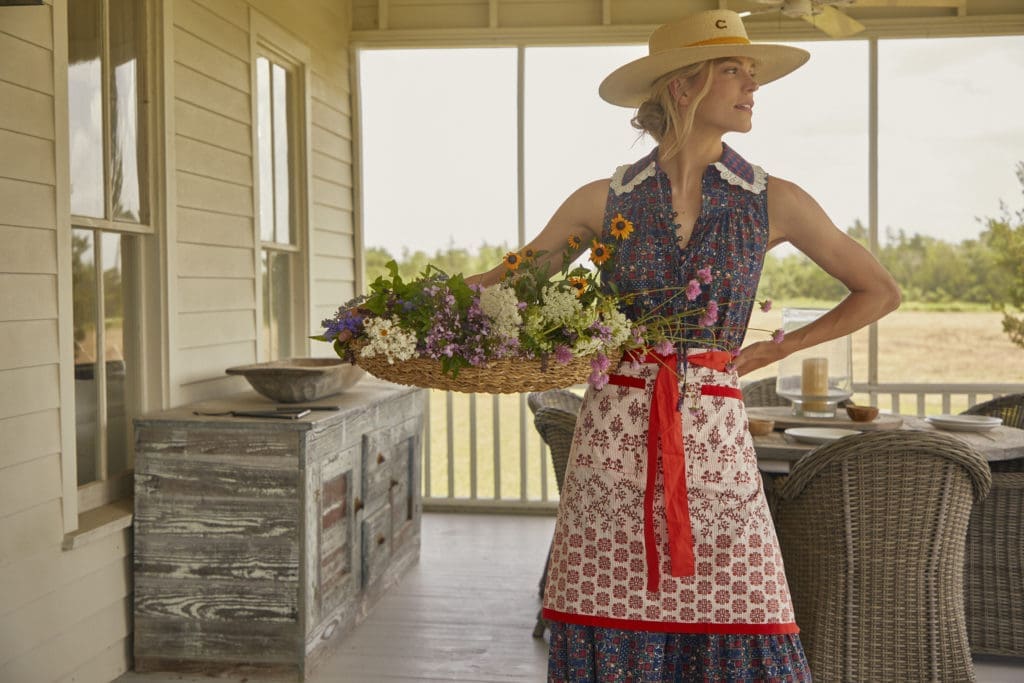 The model wears Hunter Bell's Westin dress and vintage patchwork apron in Western Willow Red.