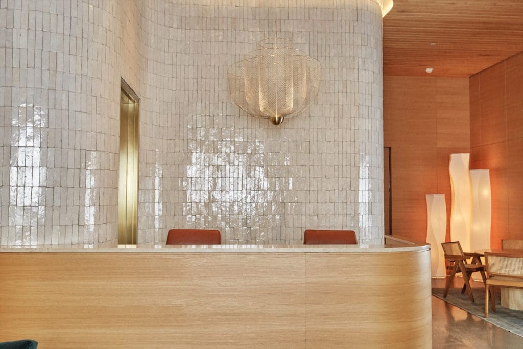 Concierge desk in white oak,
with handmade tile wall; Moooi
chandelier from Scott + Cooner. (Photo by Max Kutz)