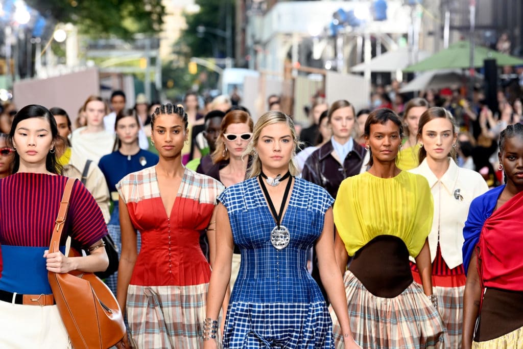 Kate Upton, center, wears a Tory Burch picnic plaid silk dupioni dress
with grid-pattern bodice, embossed Lampshade bag, and link lace-up sandal. (Photo by Slaven Vlasic/Getty Images for Tory Burch)