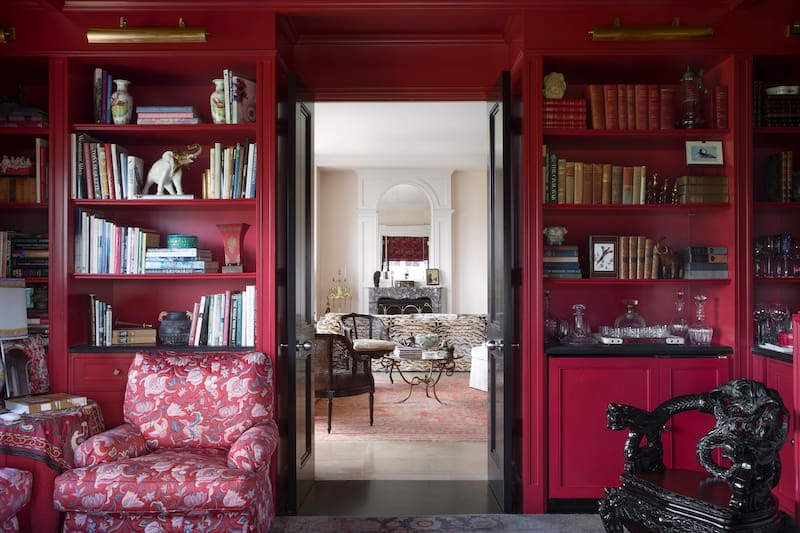 Walls and ceiling are lacquered red. Shelves hold objects picked up during the homeowner's travels. The ornately carved chair is an antique from Asia. (Photo: Emily Minton Redfield)