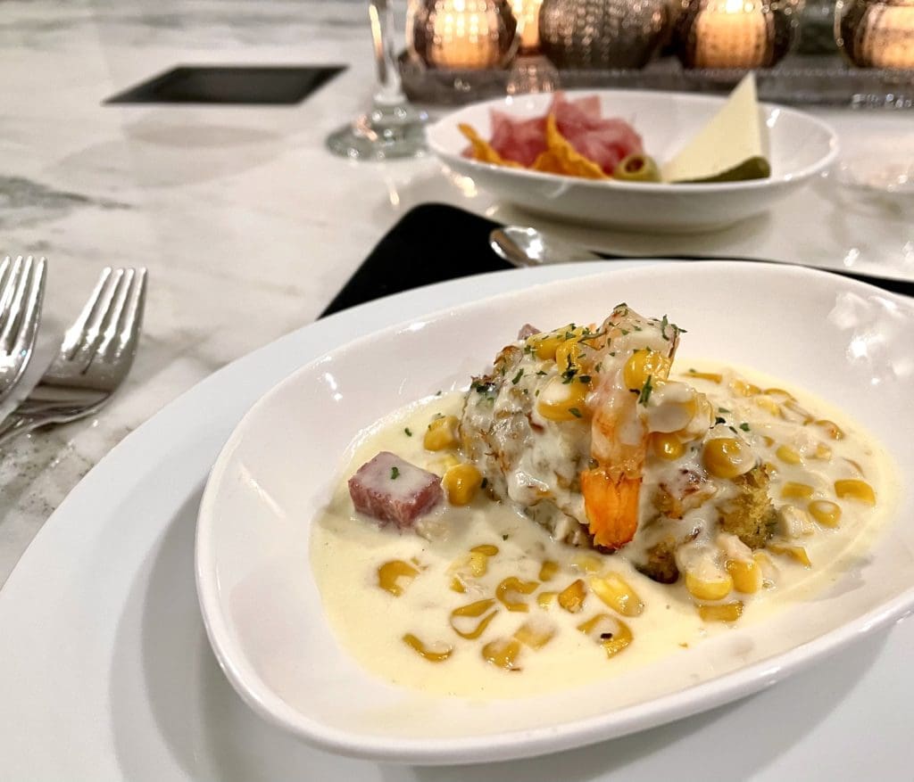 Grilled shrimp topped a lump crab cake in a corn maque choux cream sauce, with crispy pancetta. Photo by Courtney Dabney.