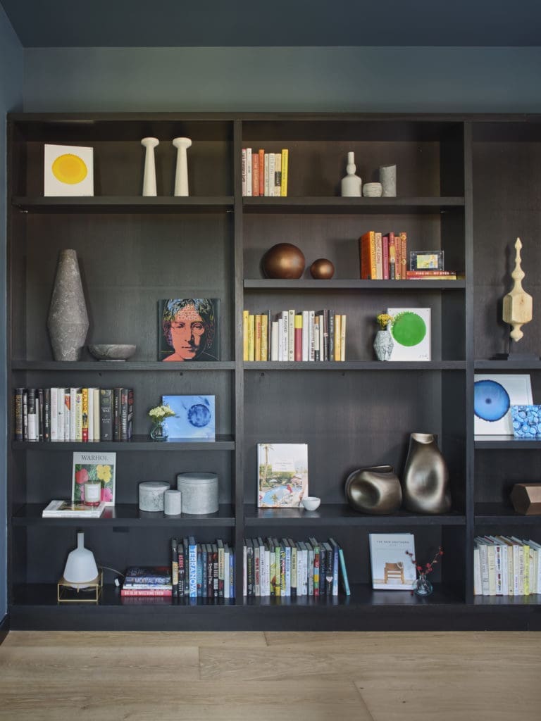 Various original artworks by John David Robbins add pops of color to the dark shelf design.