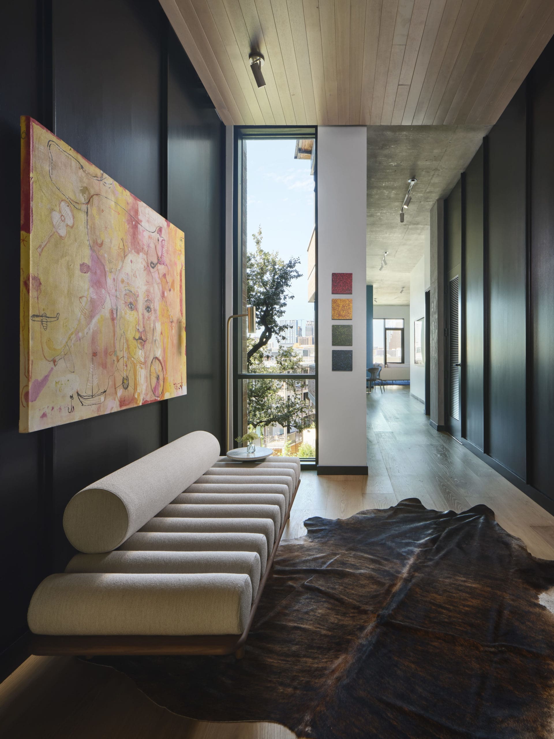A sculptural Tacchini daybed paired with authentic cowhide for traditional Texas flair in this  entry foyer.  International artwork by Yvan Genest ”From Mexico to India” and local artist John David Robbins “Drips" mini series. (Photography by Andrea Calo)