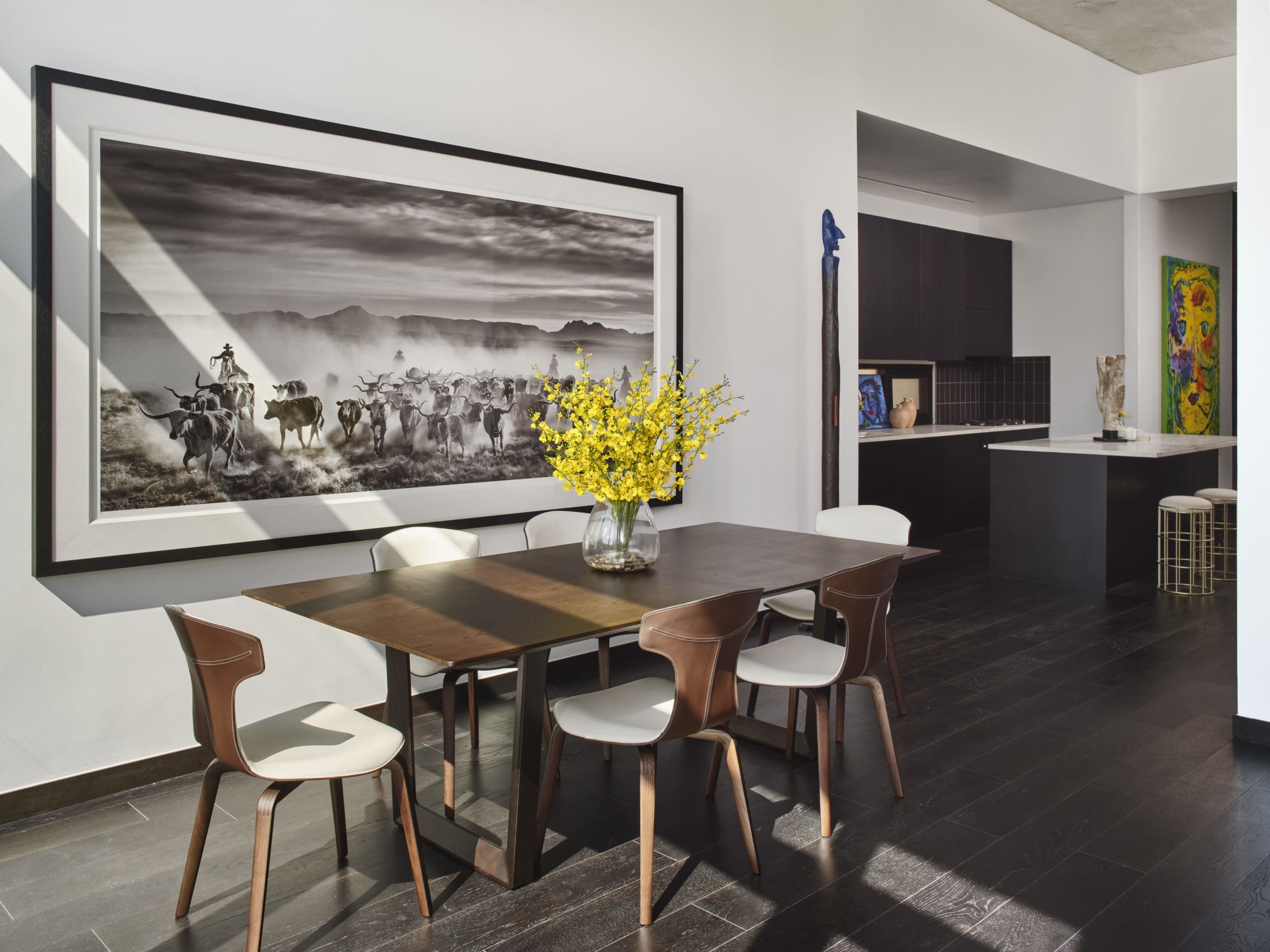 David Yarrow’s largescale “The Thundering Herd” artwork paired perfectly with a sleek Poltrona Frau dining table and
brown leather dining chairs for the light-filled dining room with floor to ceiling windows. For pops of color, Ana Tatya Neri “Punked” artwork in kitchen. (Photography by Andrea Calo)