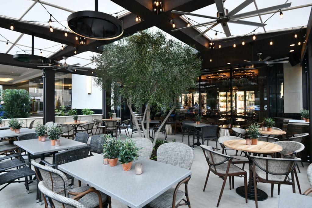The patio at Stella's Wine Bar is centered with a 13-foot olive tree and features reclaimed, solid-oak wine barrel lids that serve as patio dining table tops.