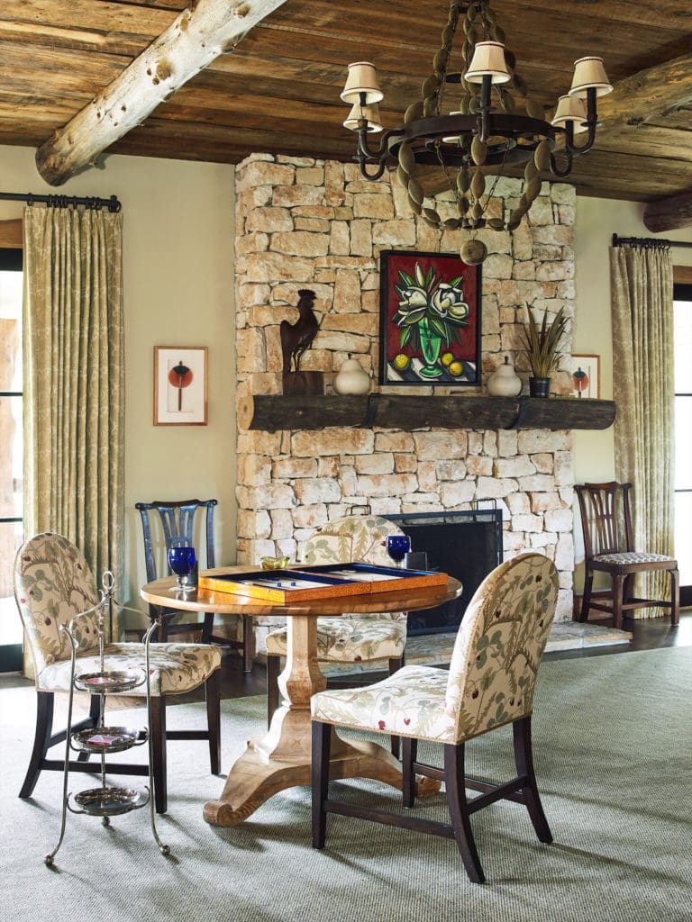 Repurposed oak ceilings, beams, and a large stone fireplace give the main living area a rustic, masculine feel. Artwork over the fireplace is by David Bates from Talley Dunn Gallery. (Photo by Tria Giovan)