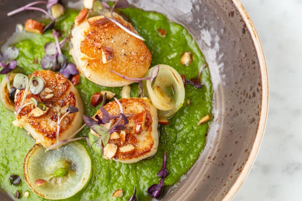 Seared scallops served with green gazpacho, charred cippolini onion, smoked almond is new to the Brasserie 19 menu. (Photo by Andrew Hemmingway)