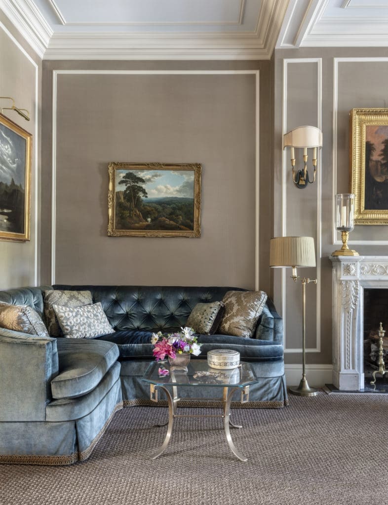 French art deco sconces with verdigris-finished frames and gilt Egyptian-influenced details, and Louis XVI–style photophores on the mantel add to the layering of history in the room.