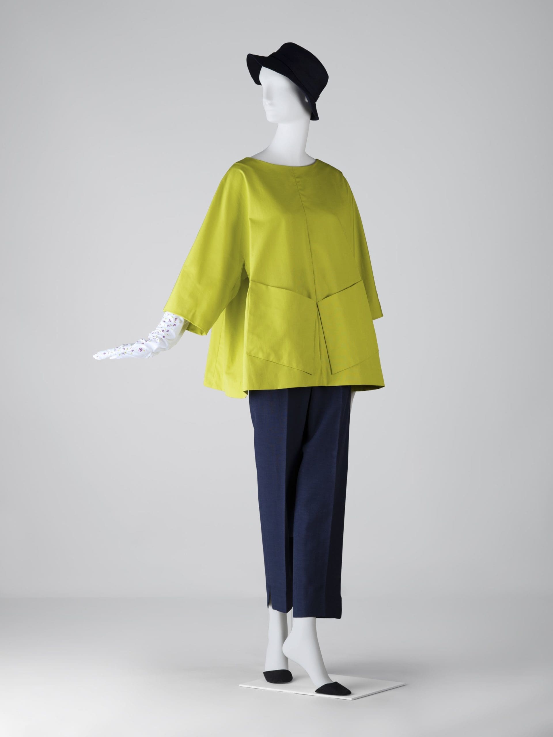 Designed for Bunny by Balenciaga, a garden tunic with diamond-shaped patch pockets, in pistachio green cotton taffeta, and her trademark blue bucket hat.