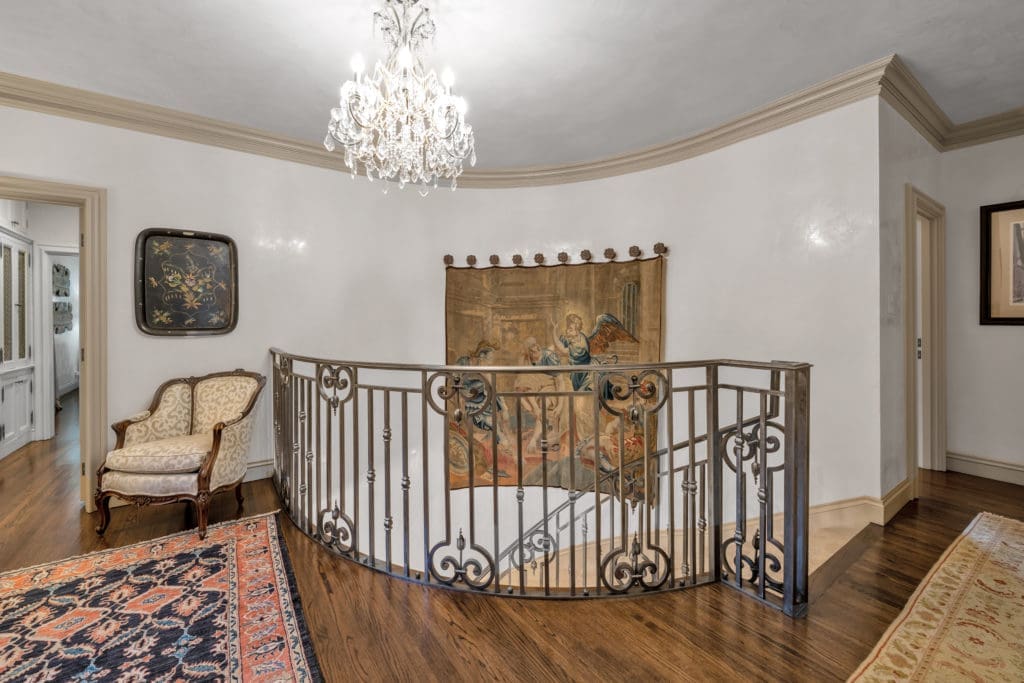 Custom iron staircase lined with Venetian plaster walls lead to the second floor landing.
