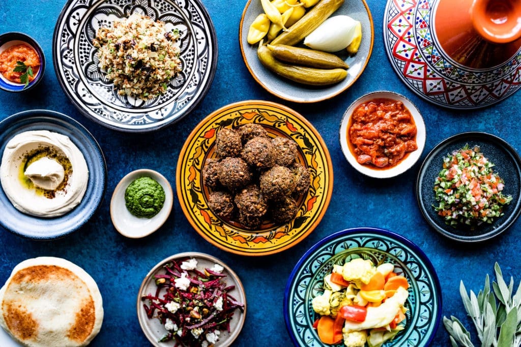 Traditionally in Israel, you start the meal with small dips, salads, and pickles called Salatim, several pictured here, surround their house made Falafel. (Photo by Kirsten Gilliam)