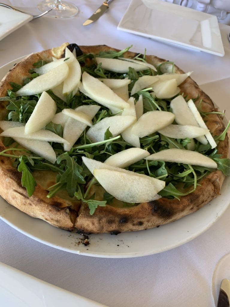 The pizza here is the thin-crusted Neapolitan sort. The pizzaiolo pulls blistered-bottom pies out of the golden-tiled oven, such as a taleggio pear variety topped with arugula, fresh Bosc pear slices, and a drizzle of truffle oil ($19). (Photo by Laurann Claridge)