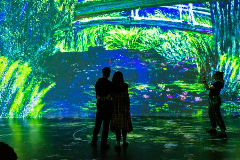 Onlookers take in a serene painting at "Immersive Monet & The Impressionists." (Photo by Patrick Hodgon)