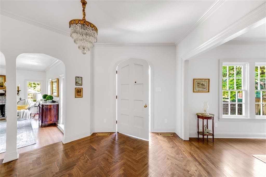 A welcoming, wedding cake chandelier and gleaming herringbone wood floors greet you in the foyer.