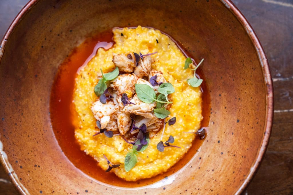 Chef Andre Garza's unctuous brunch dish, heirloom grits, are seasoned with chili laced garlic butter and topped with jumbo lump crabmeat.  (Photo by Michael Anthony)