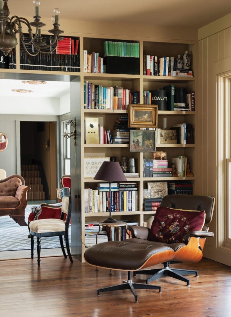 A reading nook in the library with a vintage Eames chair and ottoman. Shelves hold books on travel, art, design, history, and philosophy. (Photo by Jack Thompson)