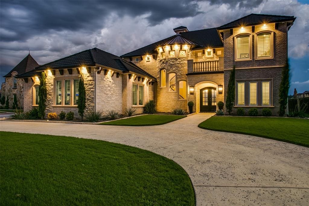 6025 Lakeside's Mediterranean exterior lit up by night.