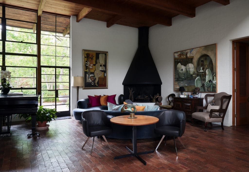 The living room’s fireplace is original. Table and chairs from Scott + Cooner, chairs from Nick Brock Antiques. At right, a Barnaby Fitzgerald painting. Left, painting by Donald Vogel. (Photo by Pär Bengtsson / art direction by Michelle Aviña)