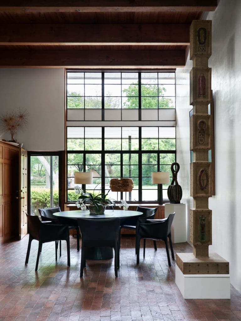 In the dining area are vintage Matteo Grassi chairs and a tall column by self-taught Louisiana artist Clyde Connell. On a pedestal, an object salvaged from a sailing ship, circa 1880, from Joel Cooner Gallery. (Photo by Pär Bengtsson / art direction by Michelle Aviña)