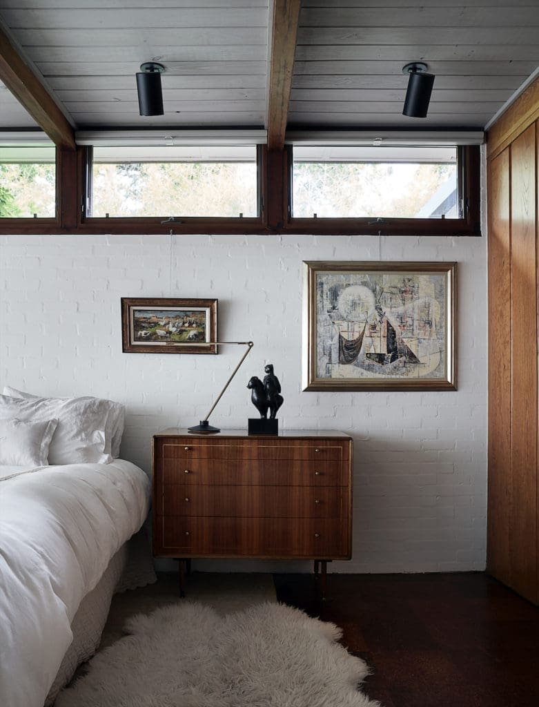 In the main bedroom are paintings by Felix Buhot, left, and Tom Benrimo. Sculpture by Pat Foss. (Photo by Pär Bengtsson / art direction by Michelle Aviña)