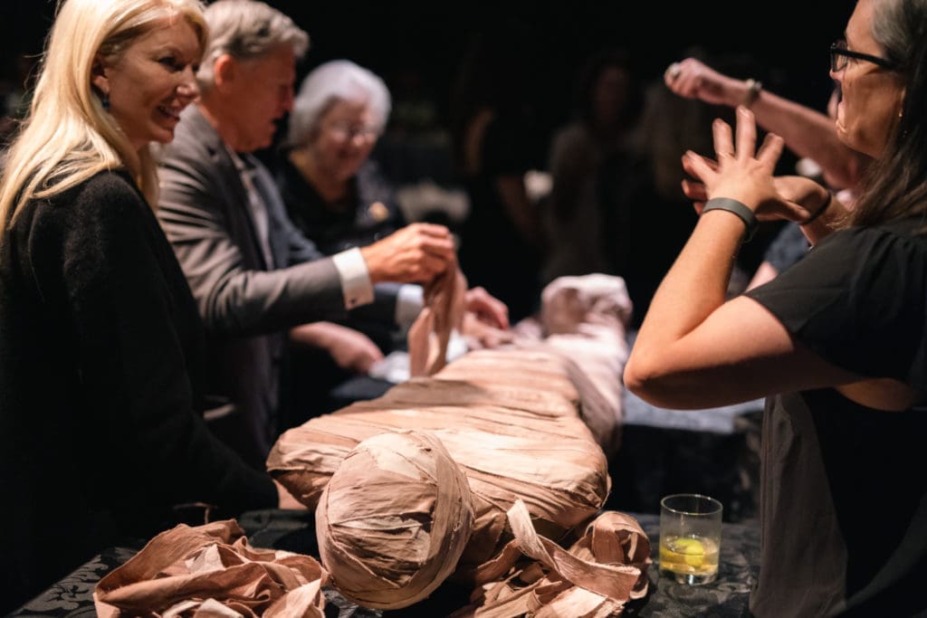 Members of the HMNS Curator's Circle assist in unwrapping a replica mummy.(Photo by Mike Rathke)