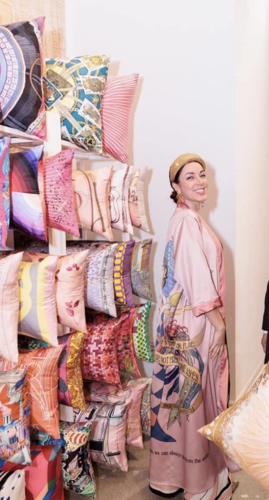 Sandra Serrani with Tribute Goods pillows on dislay at the Arsin Rug Gallery one year anniversary celebration in Decorative Center Houston. 