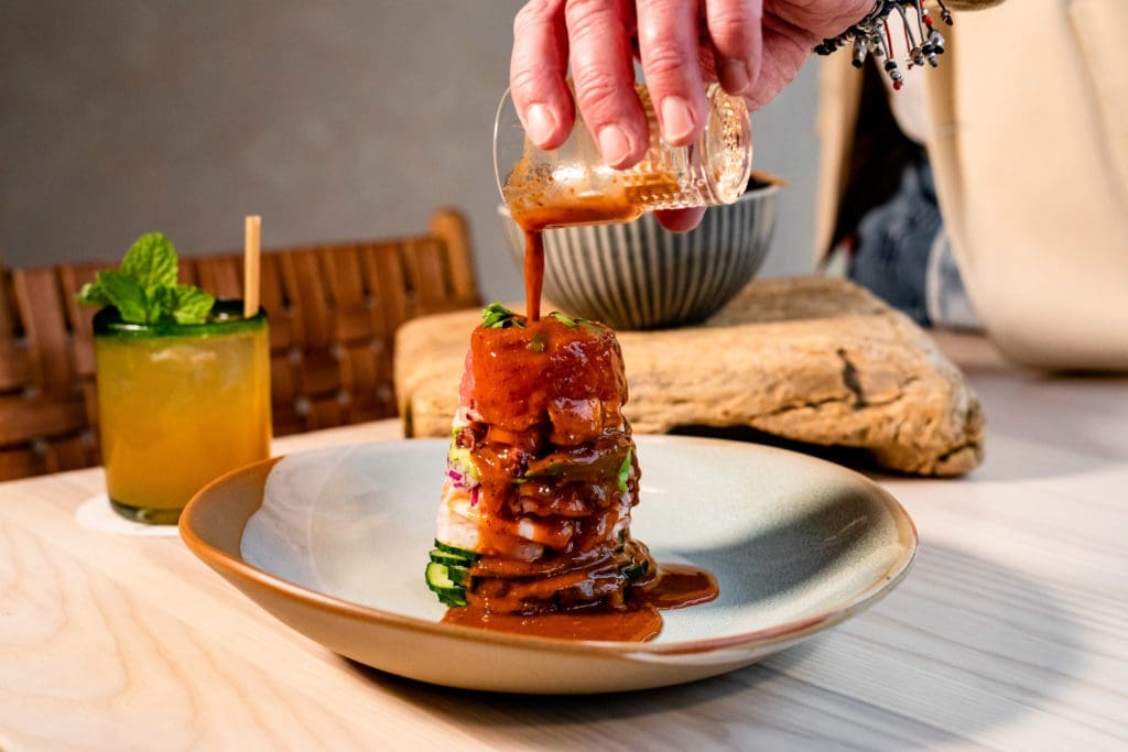 The "Ffiti Stack," short for graffiti, is composed in a clear cylinder at Graffiti Raw, the new Houston restaurant. You'll spy layers of shrimp, octopus, tuna, avocado, red onion, and cucumber. The cylinder is slowly lifted off the towering display at the table, and you are offered three different condiments/sauces to flavor it. (Photo by Kirsten Gilliam)