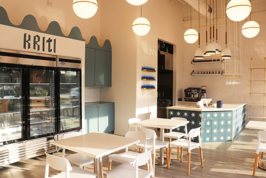 Designed by Houston-based Allie Wood Design Studio, Kriti Kitchen features modern-style dining tables and counter seating. Pops of vibrant blue cabinets and bronze globe pendant lighting give the restaurant a retro look.  (Photo by Ajna Jai)