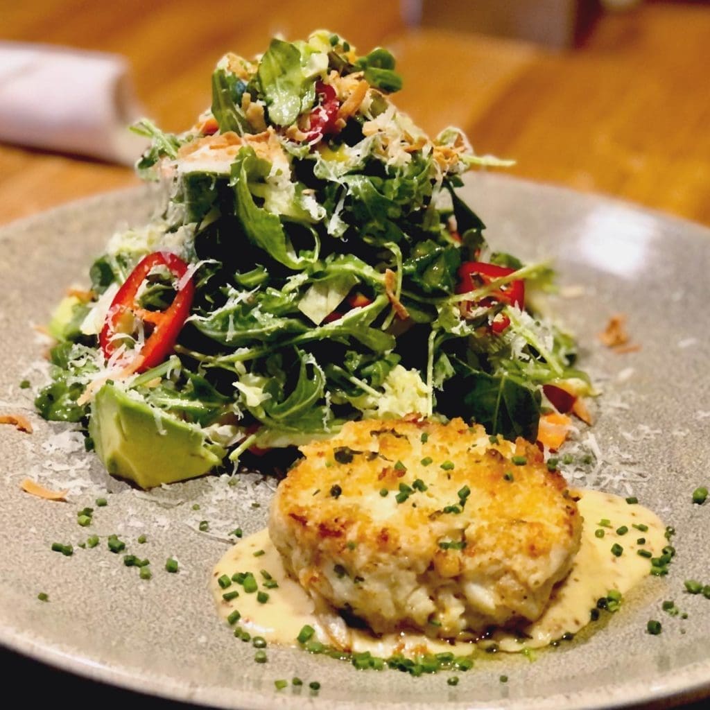 The legendary crab cake salad settles into its mustard sauce at Pacific Table.