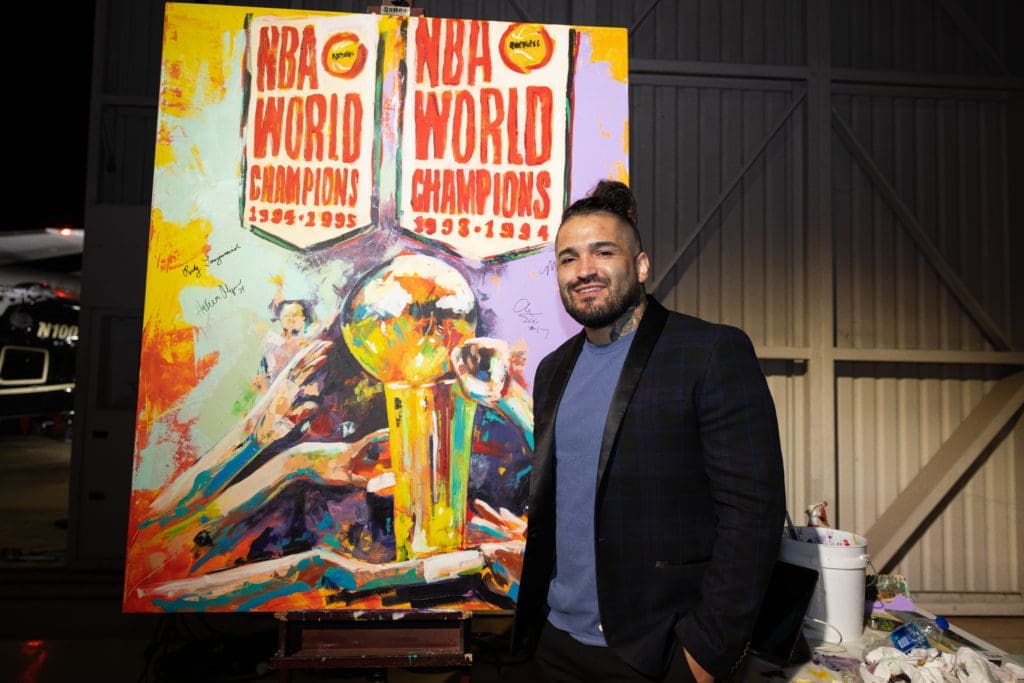 Artist Franky Cordona creates a work for auction at the Houston Rockets Clutch City Foundation gala at the Landry's hangar at Hobby Airport.