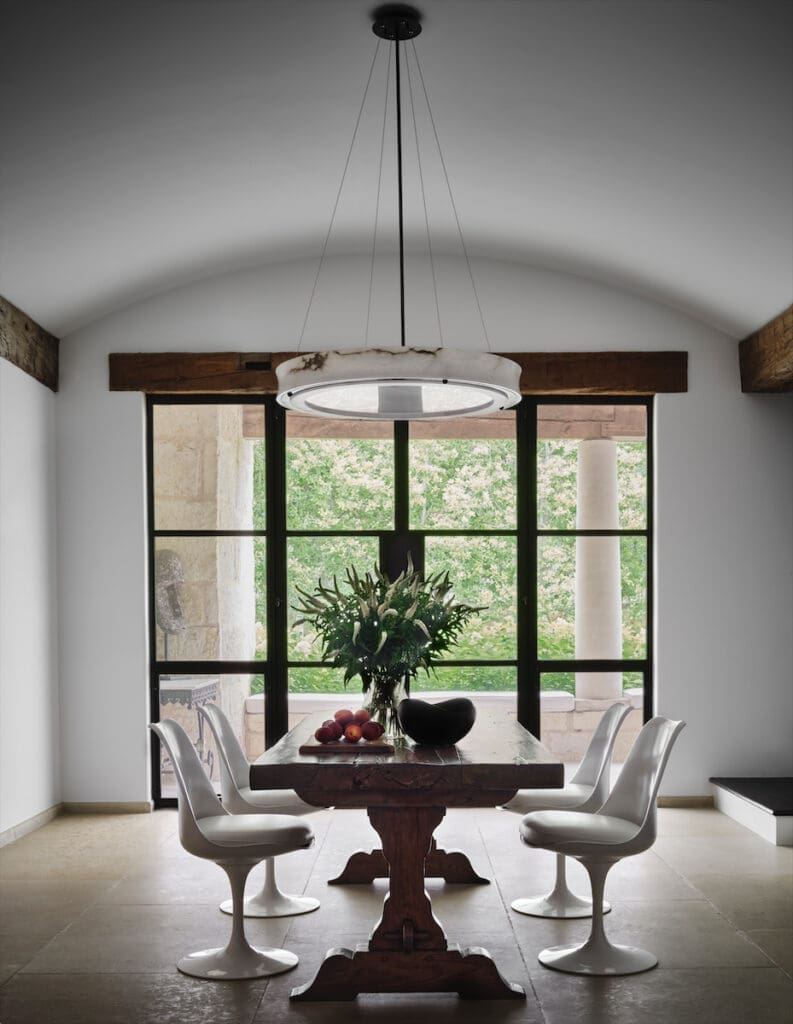 The breakfast room’s antique dining table is paired with Eero Saarinen Tulip chairs and an alabaster pendant. (Photo by Douglas Friedman)