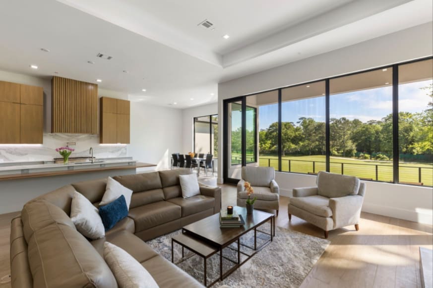 Seating and dining areas are open and share a view of the golf course at This Woodlands home.