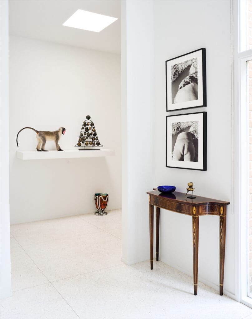 On a shelf in the entry is an ensemble sculpture by Terry Adkins. Floor vessel by Gaetano Pesce. Laura Aguilar self-portraits. Antique table holds a sculpture by Philadelphia Wireman and Elsa Peretti dish. (Photo by Jack Thompson)