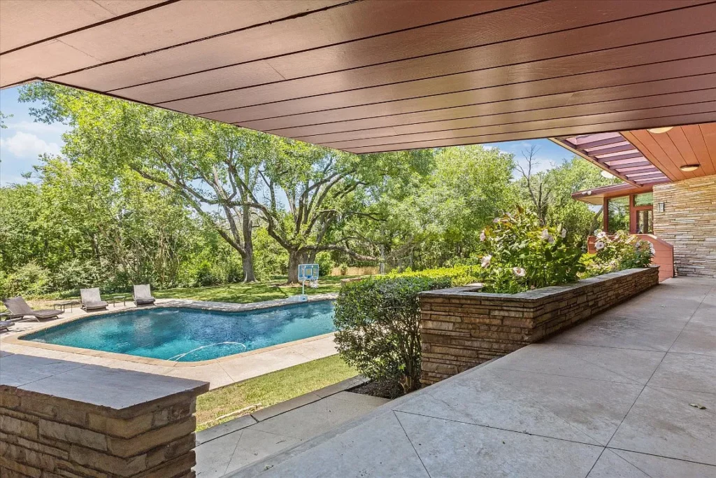 Patio stonework and heavy wooden overhangs lead to the grounds and pool.