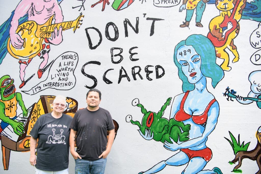 Marjory Johnston, artist Carlos Alcaraz (Empyre) at the "Don't Be Scared" mural at Redbud Arts Center (Photo by Saranna Zhang/Kevin Zhang Photography)