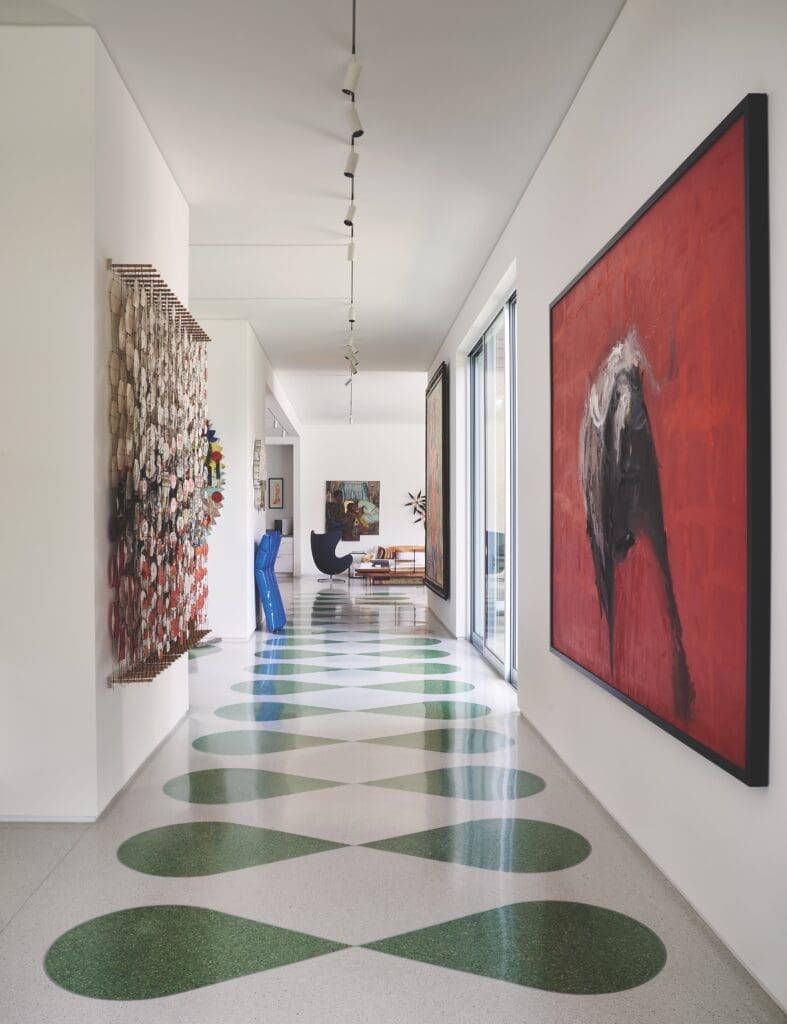 The front hallway’s custom terrazzo floors, laid by National Terrazzo Tile & Marble, were inspired by the Havana Riviera in Cuba. Right, red painting by Tonio Trzebinski. Left, Jacob Hashimoto’s kites. Metal pool float sculpture by Will Cannings. Vintage egg chair. Painting by Inga Kimberly Brown. Small orange boot lithograph by Andy Warhol.  (Photo by Pär Bengtsson)