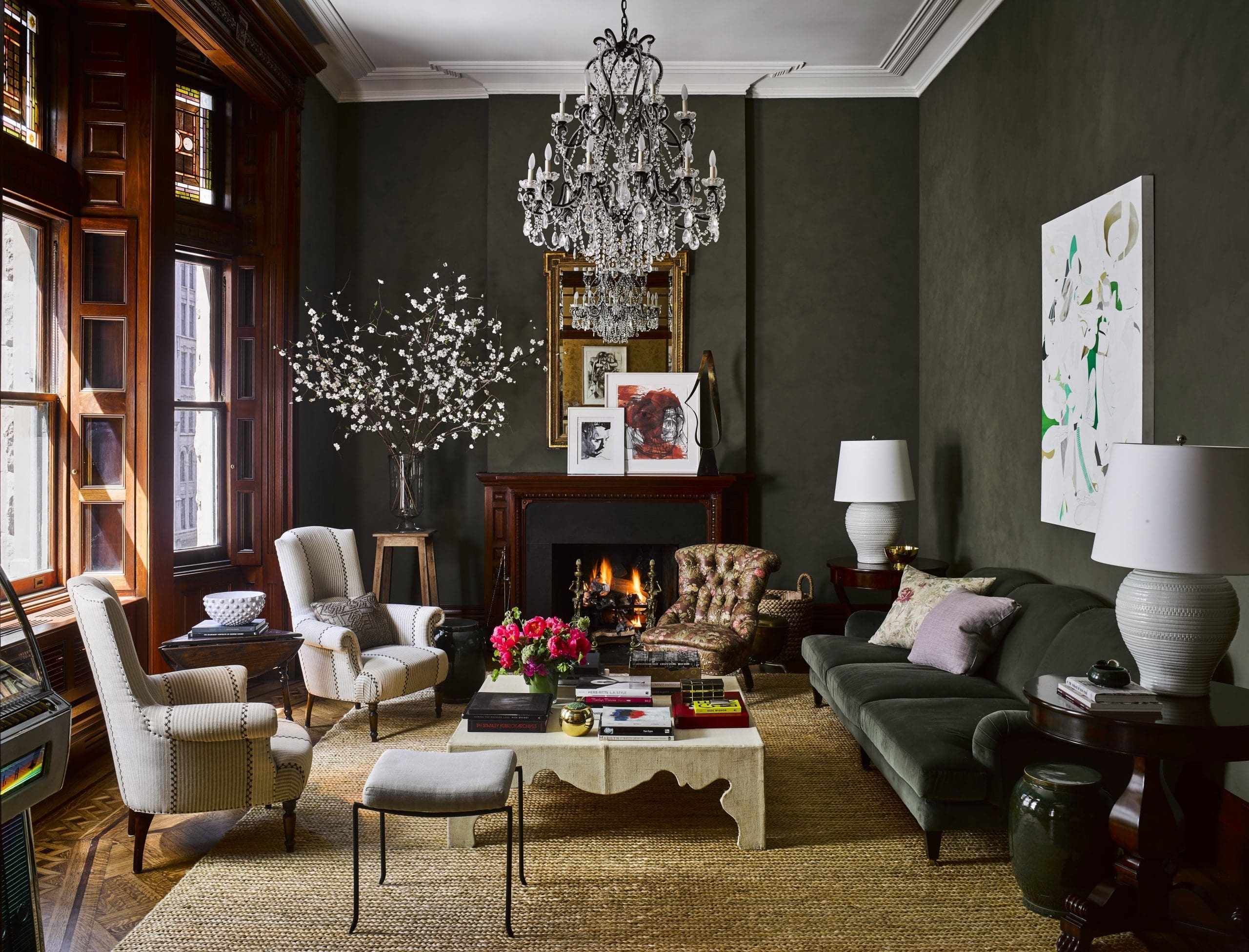 In a living room designed by Carrier and Company, deep-green-saturated walls and sofa, a neoclassical gilt mirror, and lounge chairs recall the apartment’s original period. The slipper chair belonged to Lauren Bacall. On the mantel are artworks by Thomas Libetti and George Condo. The majority of the furnishings, including furniture, fabrics, paint, lighting, and floor coverings, throughout are from Ralph Lauren Home except where noted. (Photo by Douglas Friedman) 