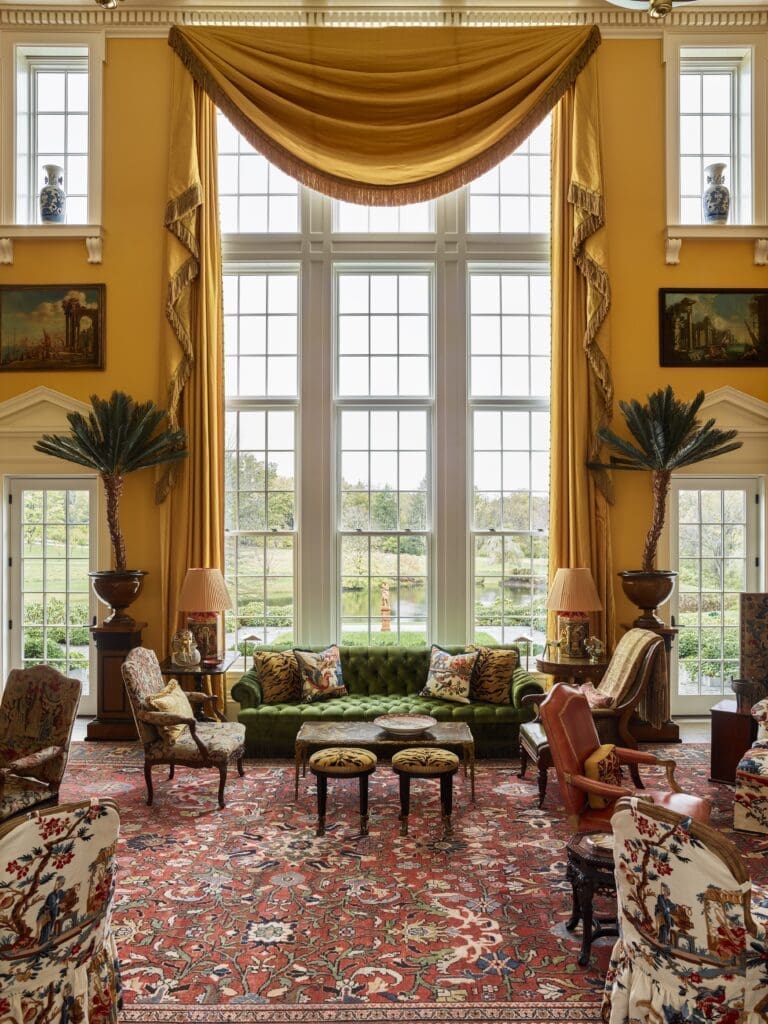 The great window in the double-height living room overlooking the pond, designed by Peter Pennoyer, is flanked by pedimented doorways and upper windows supported by brackets. (Photo by Eric Piasecki)
